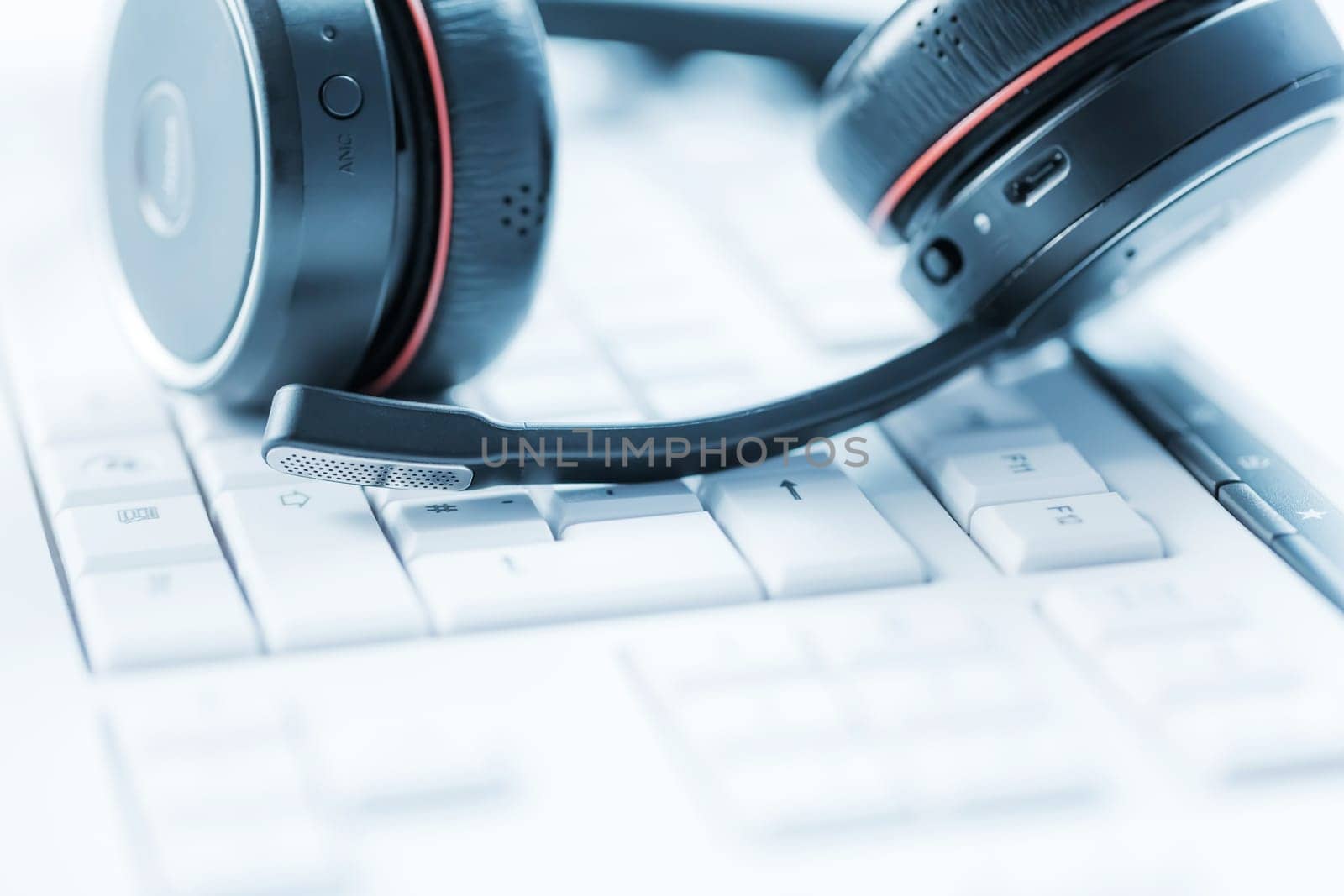 Concept of communication support, call center and customer service help desk. Headphones on keyboard. Soft focus.