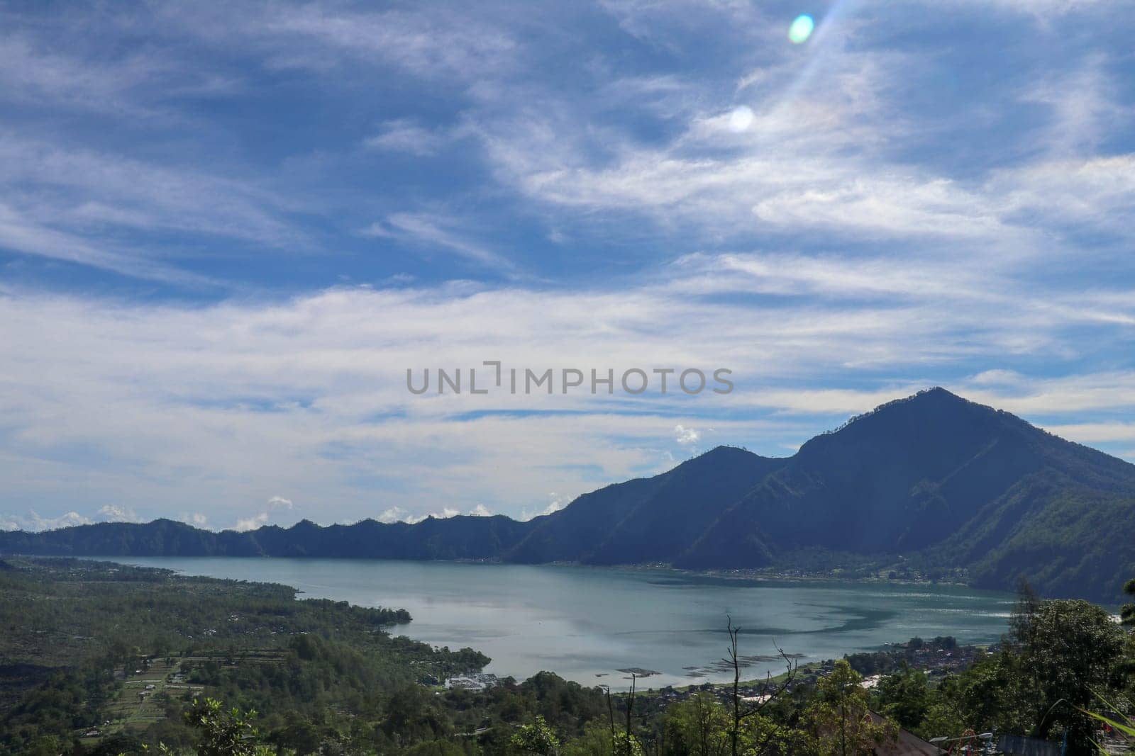 The lake Batur in the volcanic caldera of Batur under Mount Abang on the island of Bali, Indonesia. Quiet level of a large drinking water reservoir. High mountain peaks rise above the lake. Background