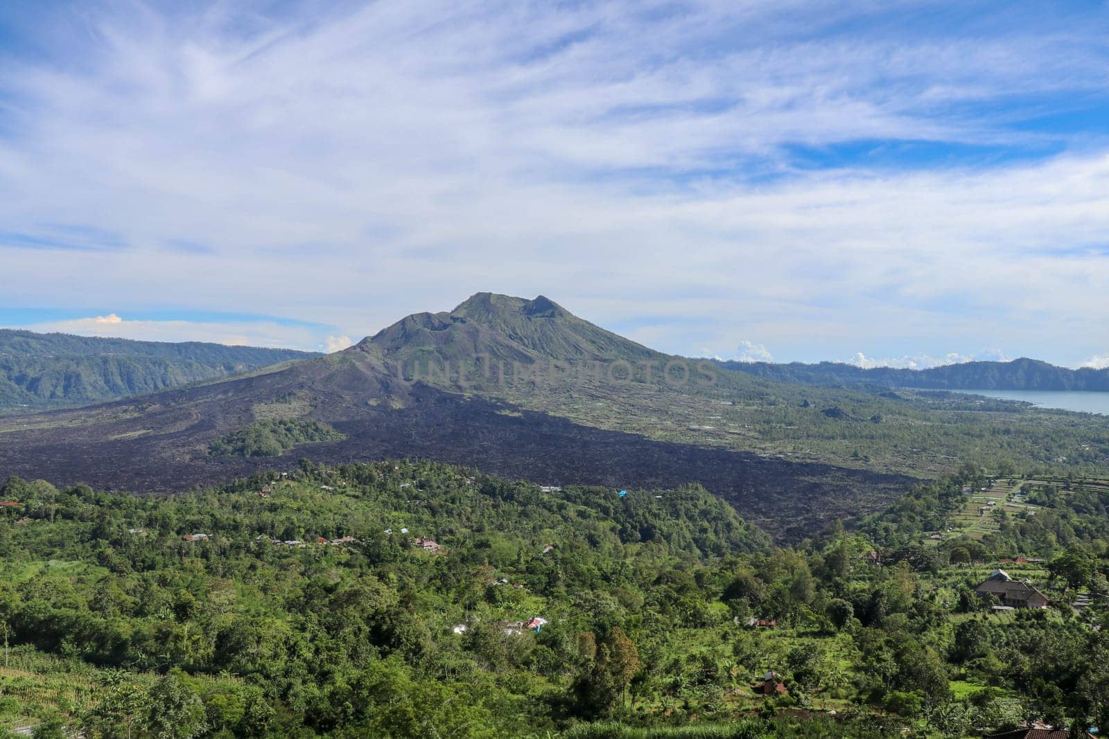 An idyllic view to the top of Mount Batur and the Danau Batur lake. There is a pathway along Batur volcano's rim. Volcanic landscape of Bali, Indonesia. Island hiking. Aerial view at Caldera Batur.