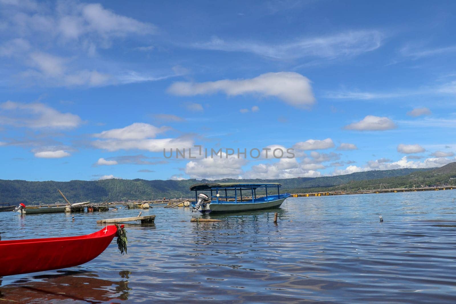 Boat traveling on the lake near the Trunyan Village of Bali. Life of Trunyan Village at Batur Lake and Volcano, Kintamani, Bali, Indonesia. This village is one of culturally isolated Bali Aga village.