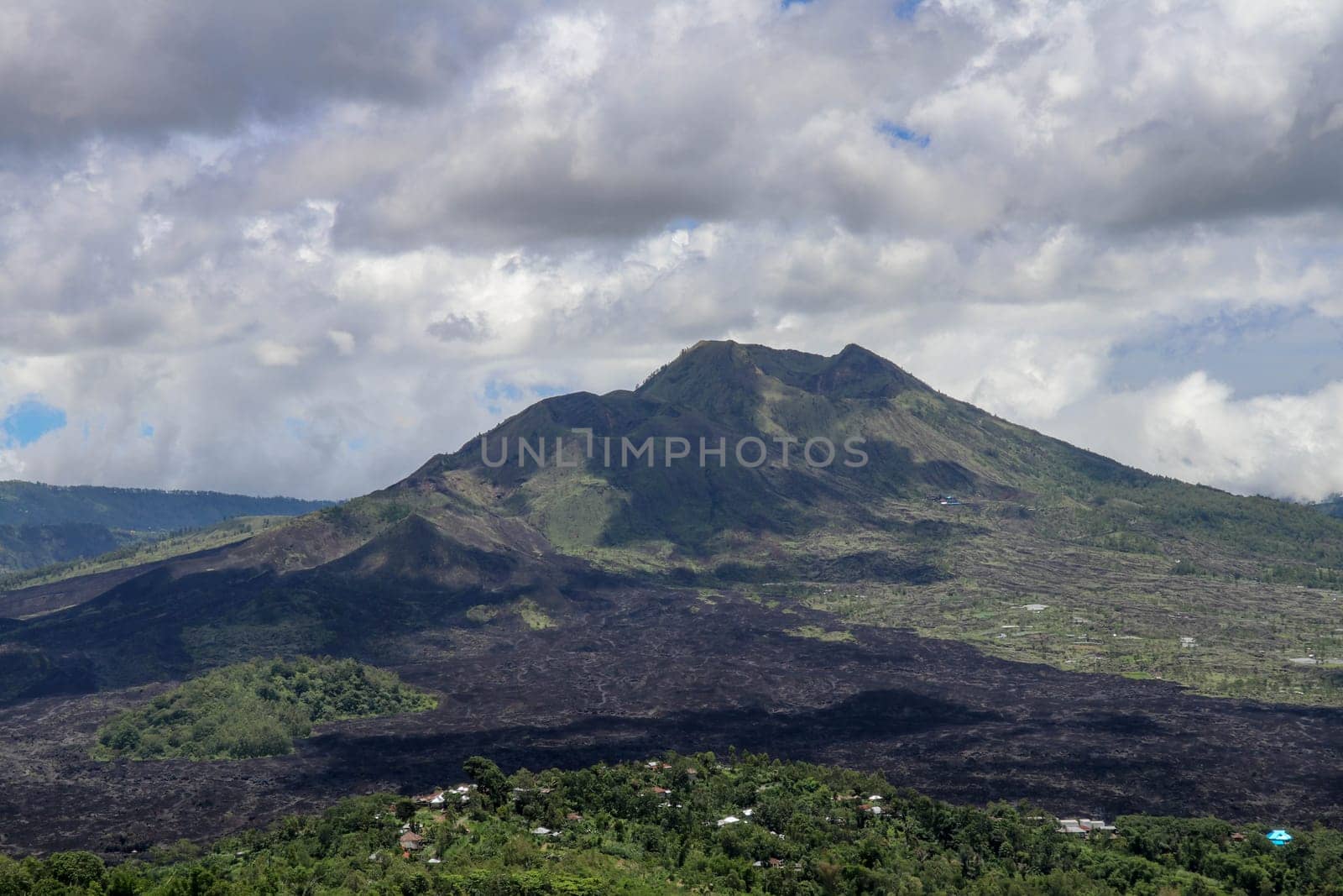 Volcano landscape with lava fields, pine tree forest and farms and houses on the slopes. Kintamani is a village on the western edge of the larger caldera wall of Gunung Batur in Bali, Indonesia.