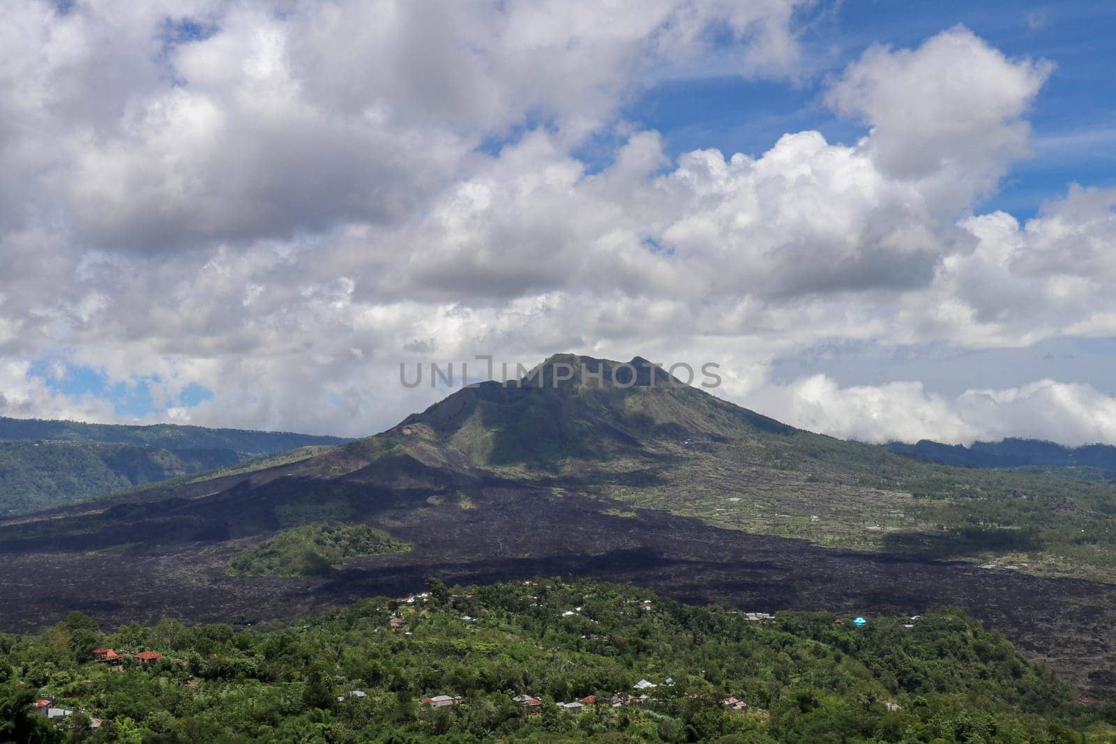 Volcano landscape with lava fields, pine tree forest and farms and houses on the slopes. Kintamani is a village on the western edge of the larger caldera wall of Gunung Batur in Bali, Indonesia.