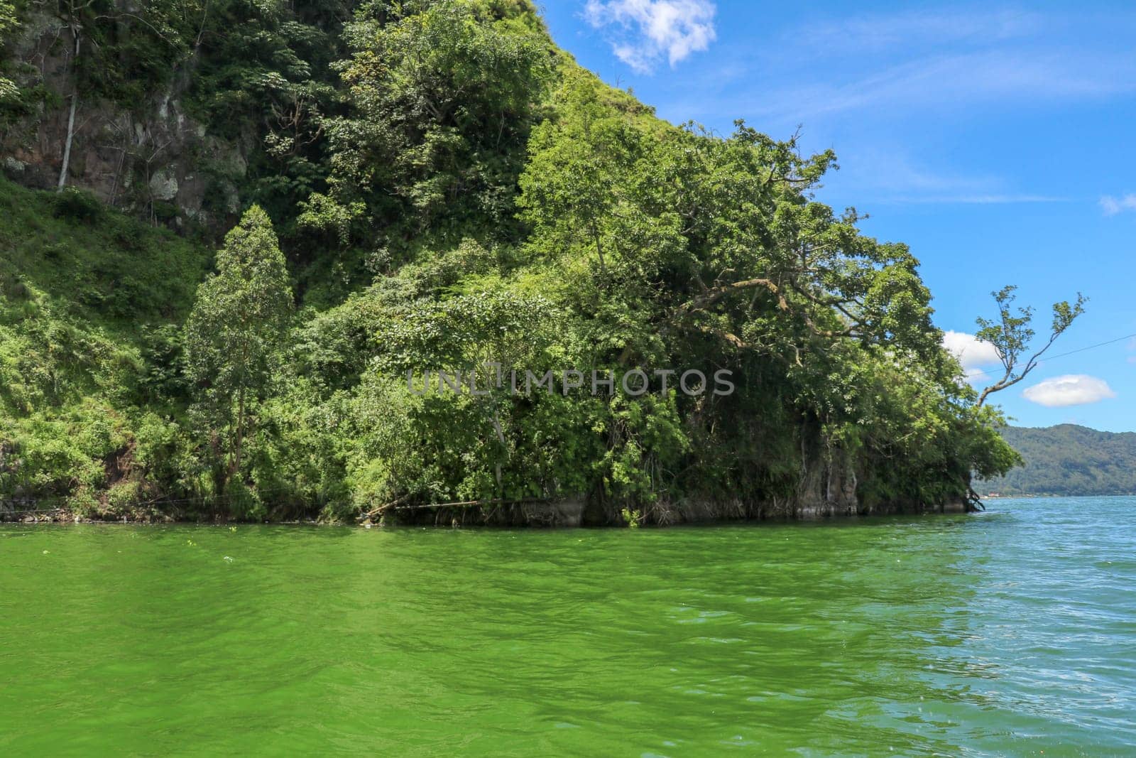 Sailing a traditional fishing boat from the village of Trunyan to a unique cemetery. High mountains covered with dense tropical vegetation line the coast of Lake Batur on the island of Bali, Indonesia