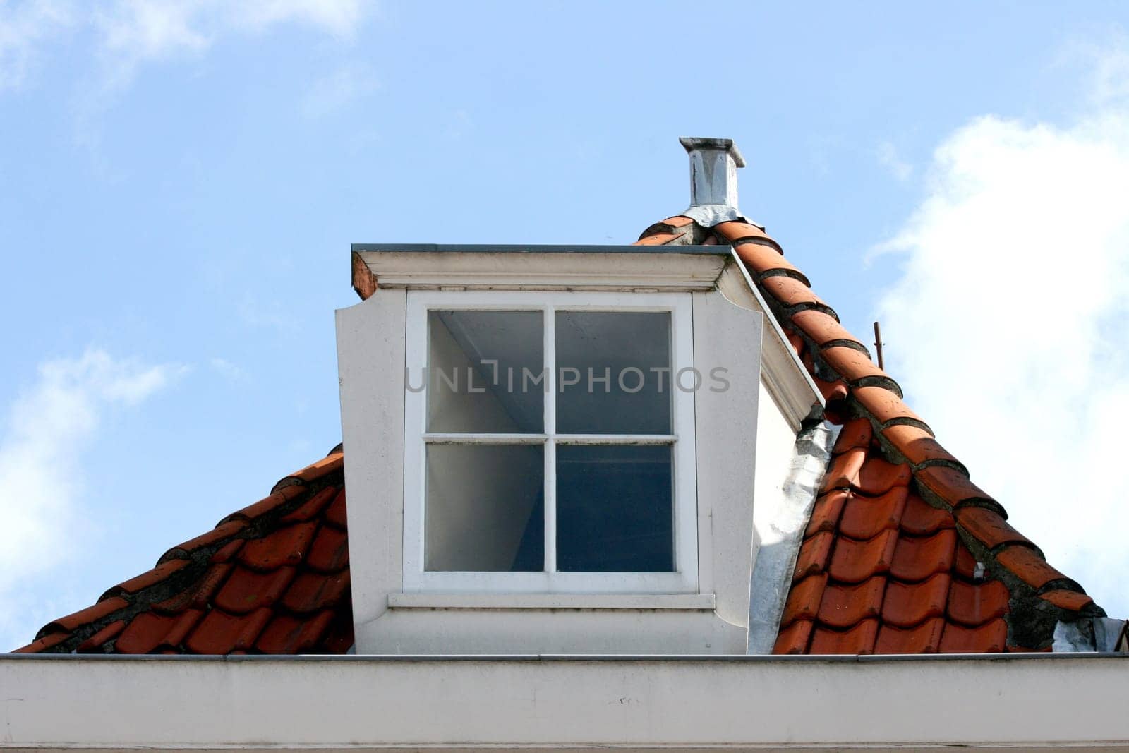 A skylight on red tiled roof, blue sky in the background.