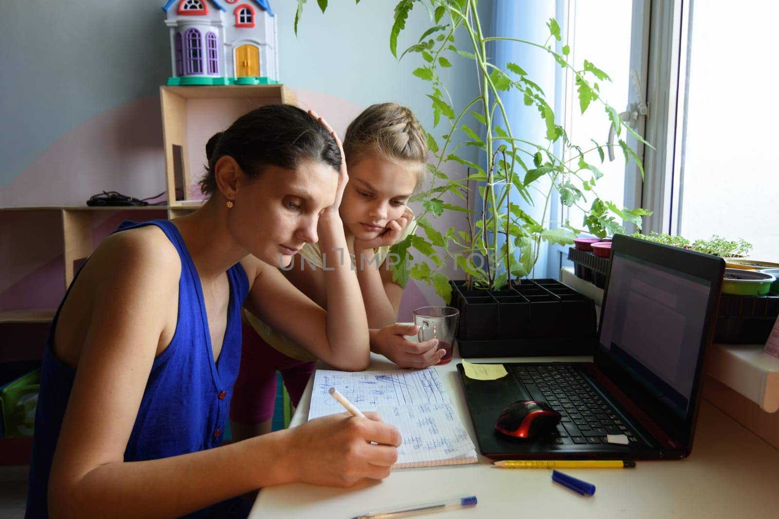 tutor explains to the child how to do the job in a notebook
