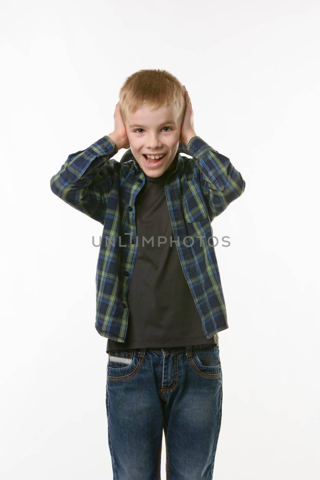 The boy covers his ears with his hands and shouts looking into the frame against a white background