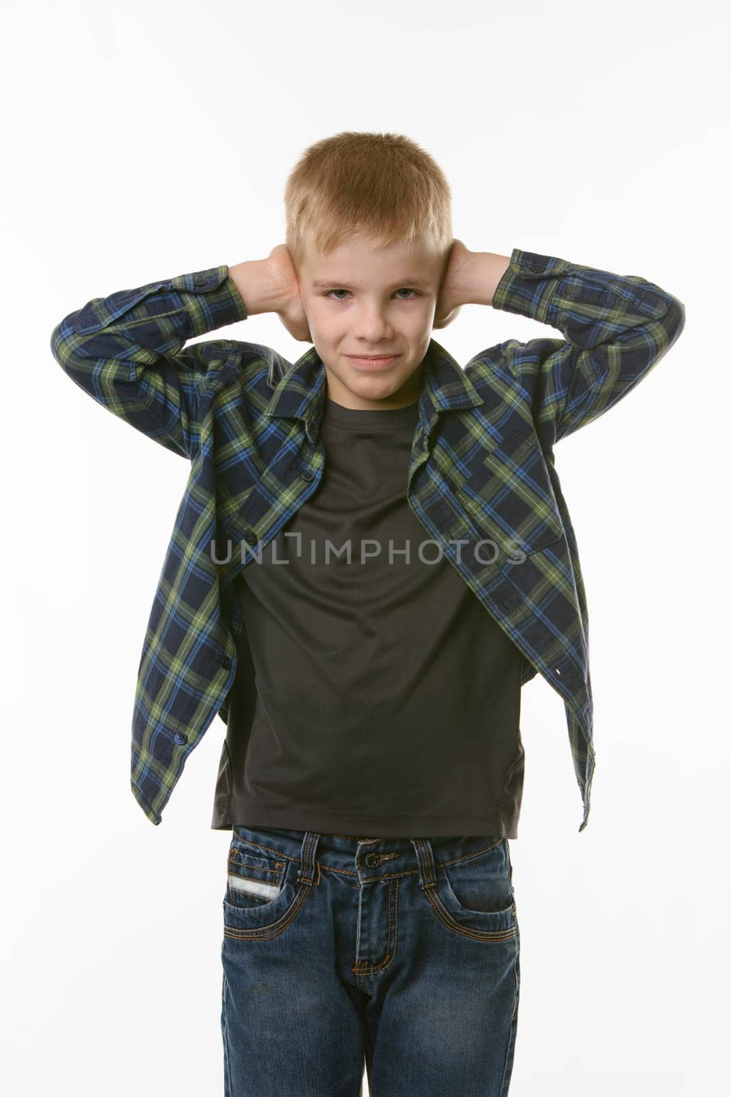 Boy covers his ears with his hands on a white background in everyday clothes