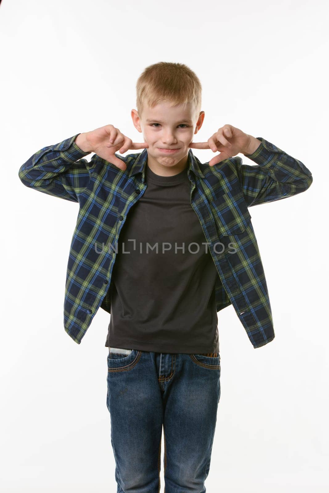 boy on a white background in a plaid shirt blows his cheeks with his fingers