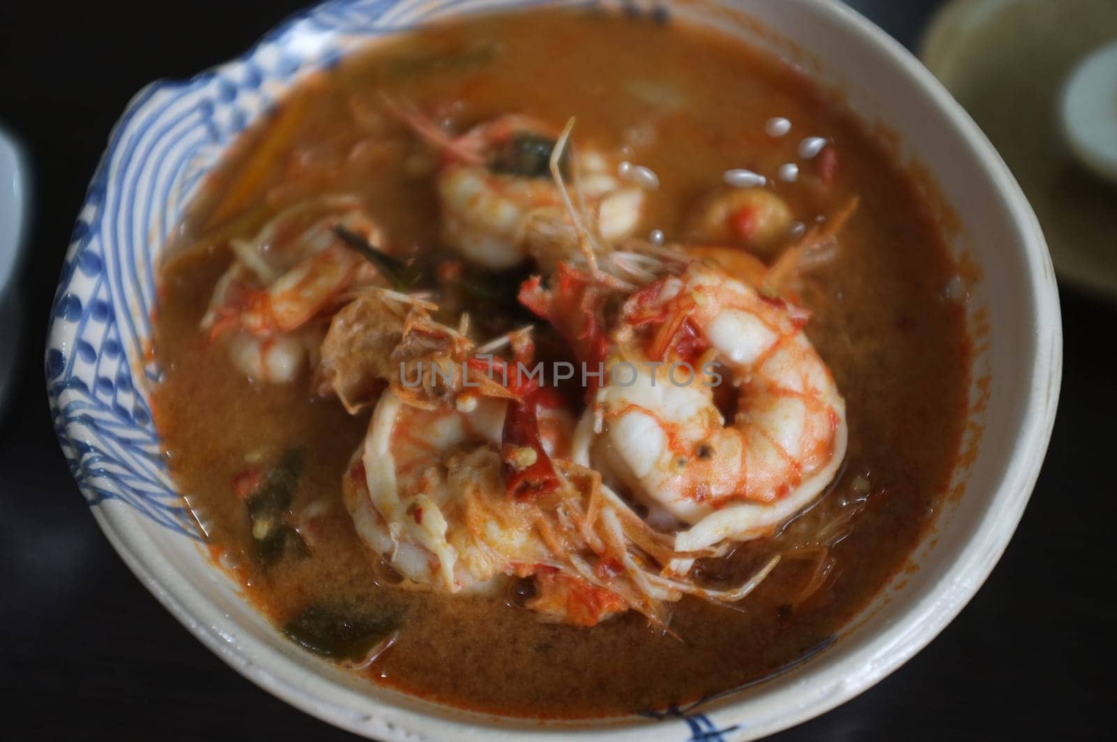 Tom Yum Goong Spicy Sour Soup or River prawn spicy soup on wood table . Thai food