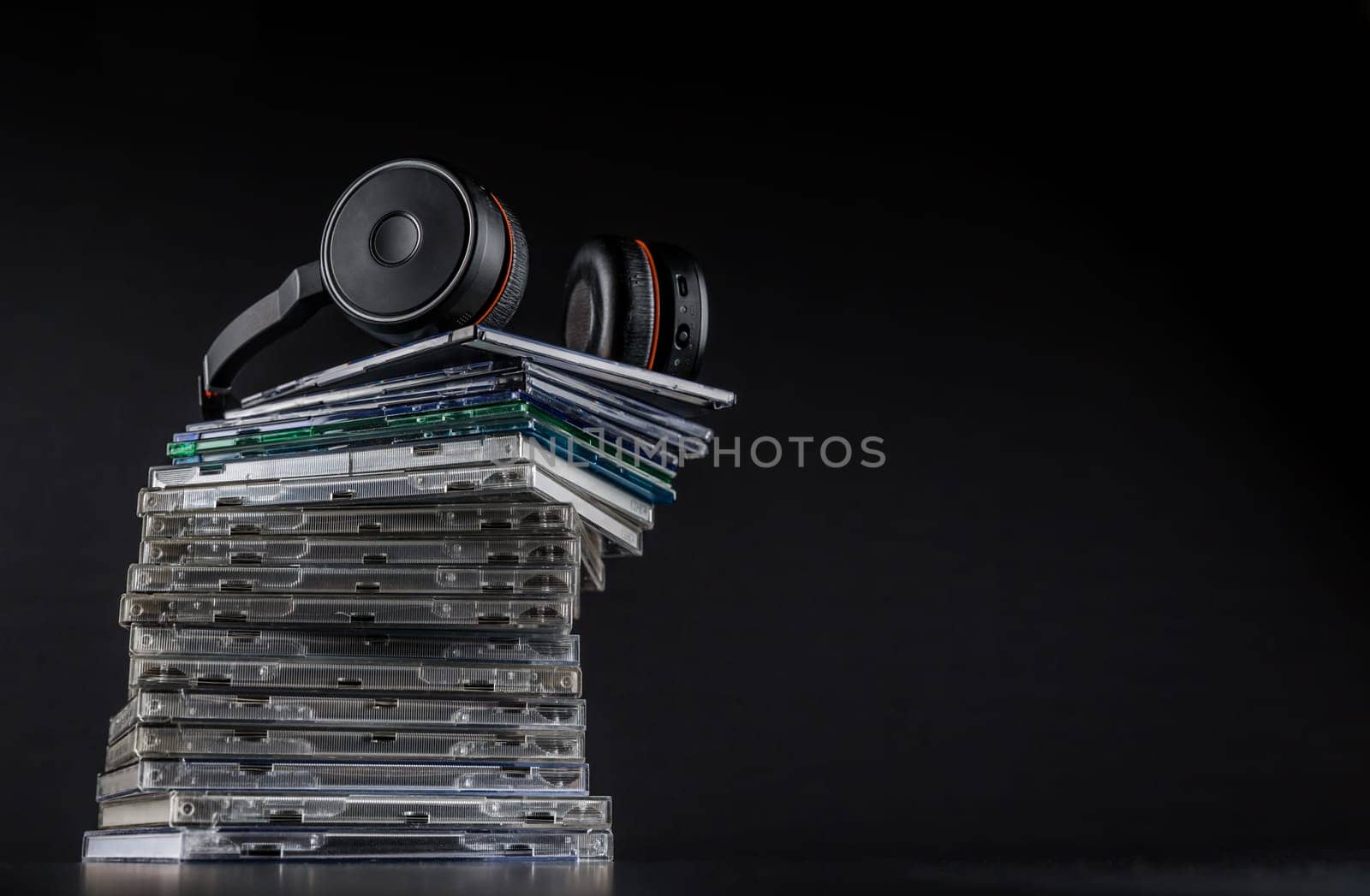 Hi-Fi headphones on stack of CDs on black background with copy space.