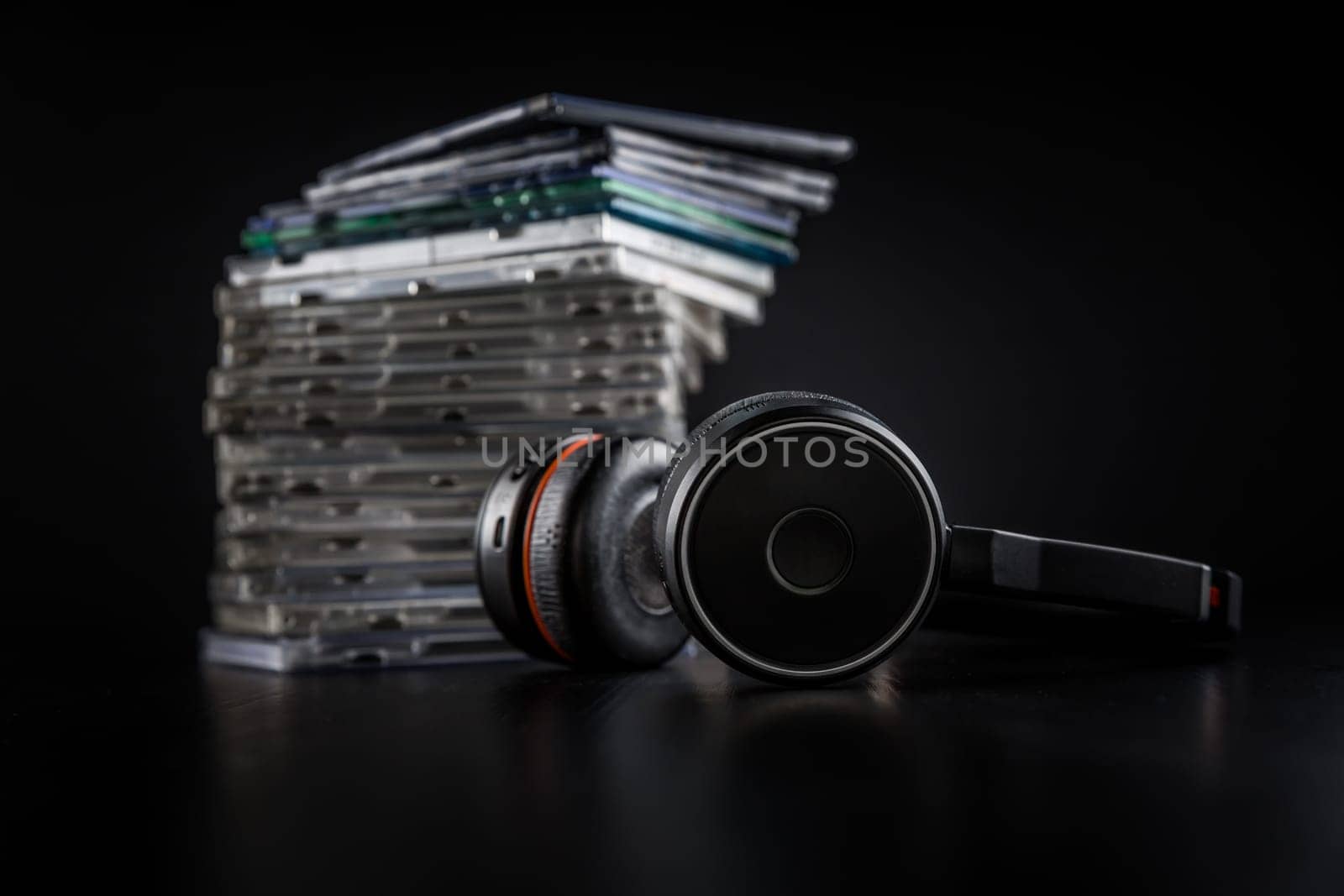 Hi-Fi headphones on stack of CDs on black background with copy space.
