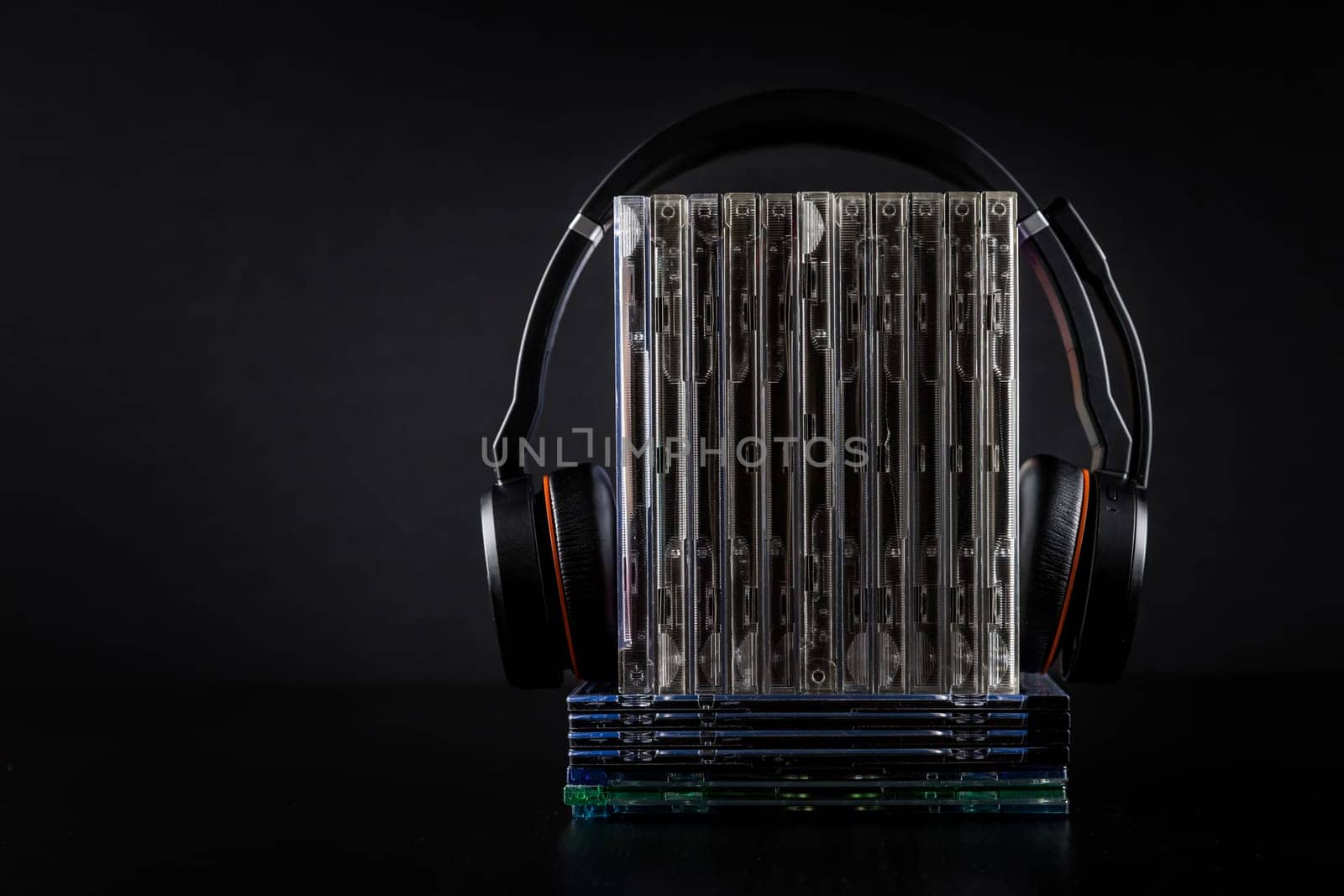 Hi-Fi headphones on stack of CDs on black background with copy space.