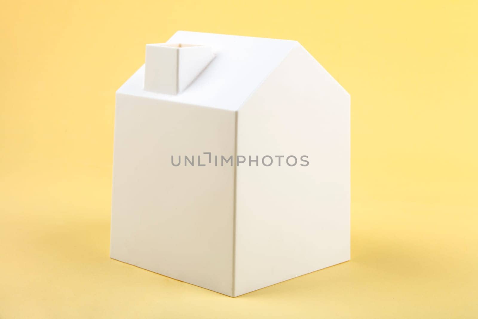 White plastic model house on yellow background