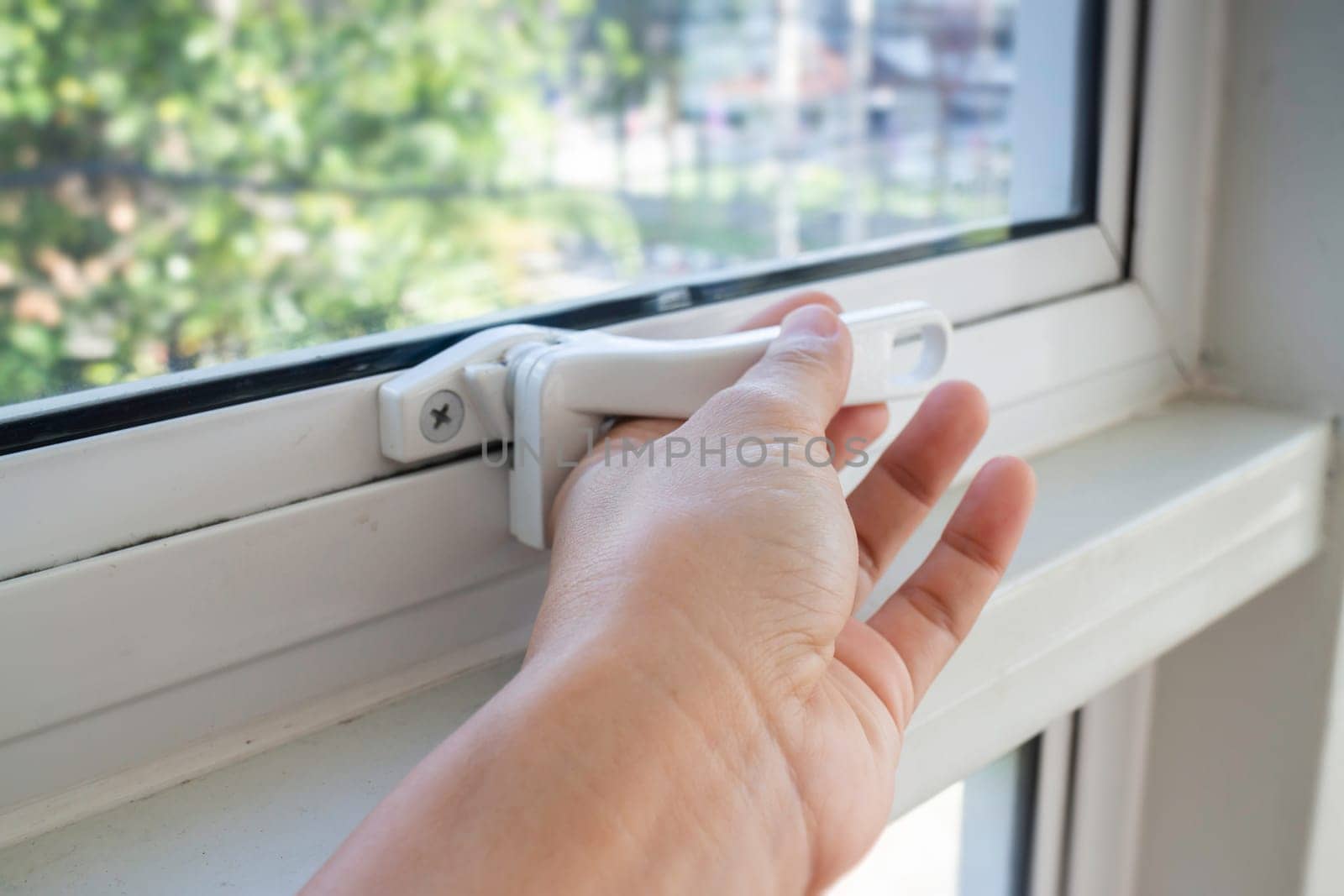 Hand holding glass window latch lever, stock photo