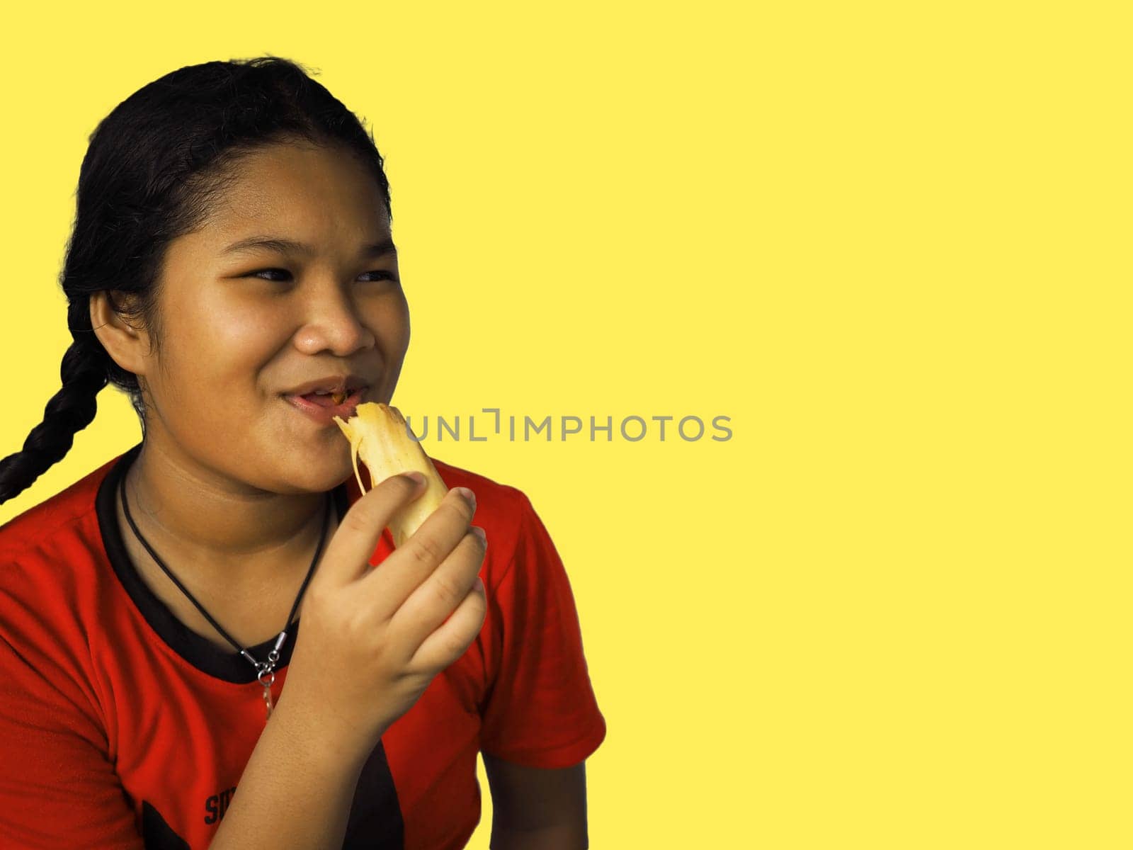 The girl eats hot dog Happily Isolated on a yellow background..Embed clipping path..Junk food concept.