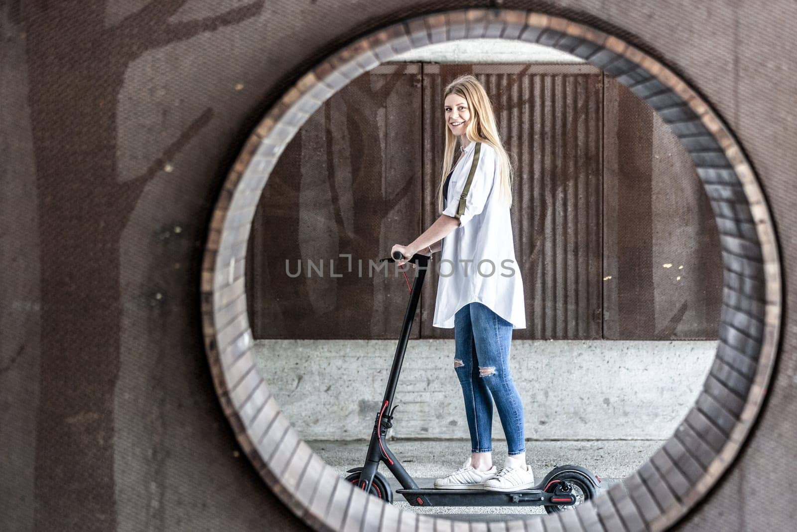 Casual caucasian teenager riding urban electric scooter in urban environment. Urban mobility concept.