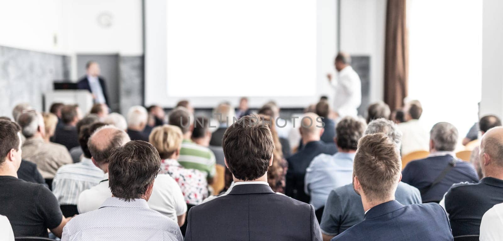 I have a question. Group of business people sitting at the chairs in conference hall. Businessman standing up asking a question. Conference and Presentation. Business and Entrepreneurship.