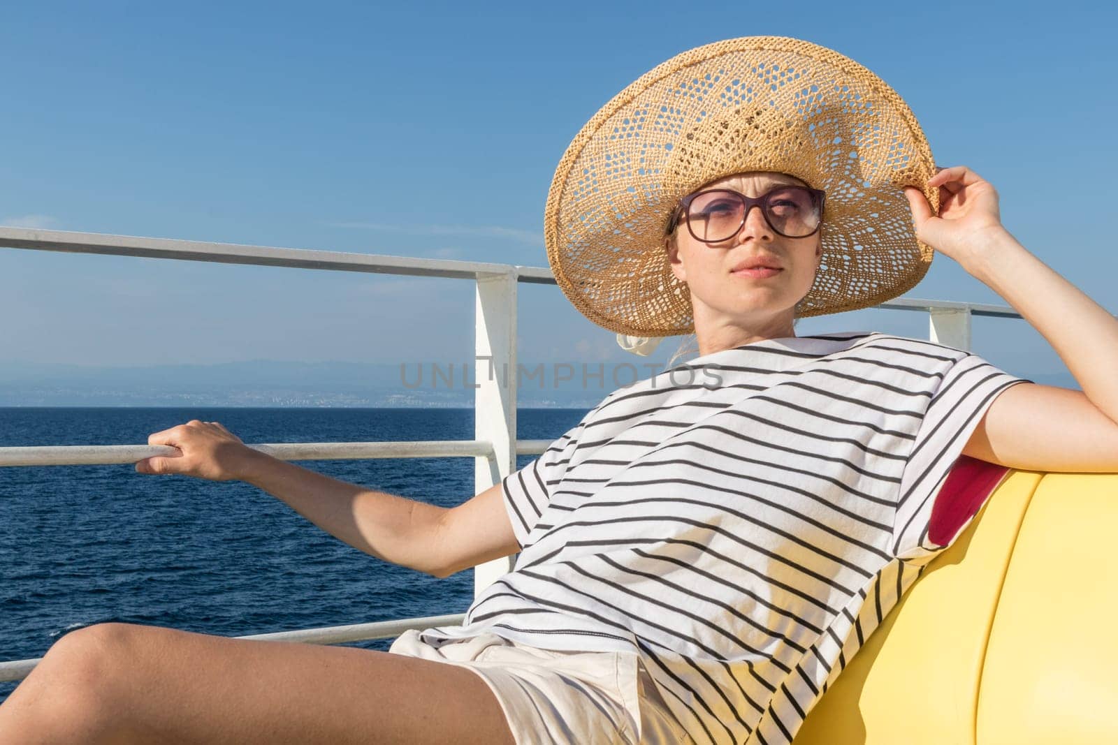Beautiful, romantic blonde woman relaxeing on summer vacations traveling by cruse ship ferry boat. Summer vacation lifestyle.