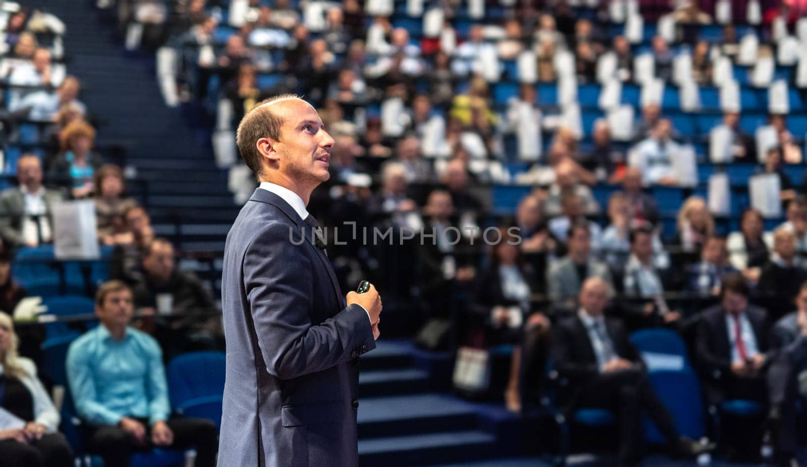 Speaker giving a talk on corporate business conference. Unrecognizable people in audience at conference hall. Business and Entrepreneurship event.