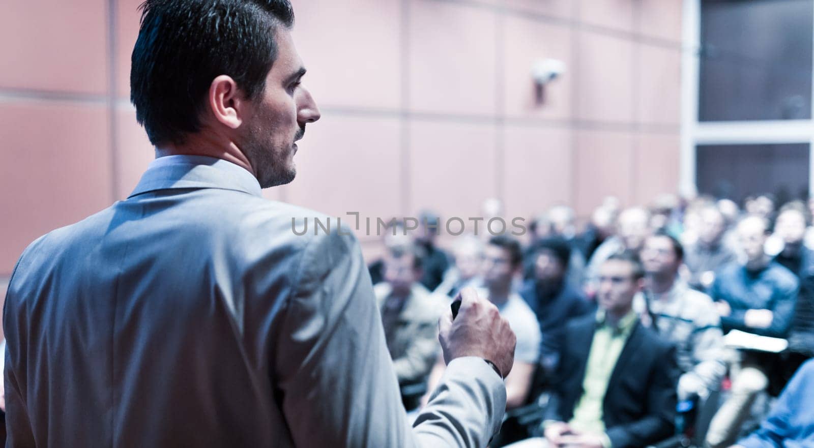 Speaker giving a talk on corporate business conference. Unrecognizable people in audience at conference hall. Business and Entrepreneurship event.