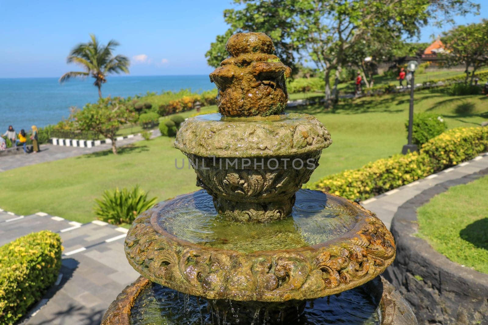 Peaceful scenery with fountain. Park near the Hindu Temple Tanah Lot, Bali, Indonesia. Small decorative fountain in tropical garden for landscape design. Stone three-stage fountain with running water.