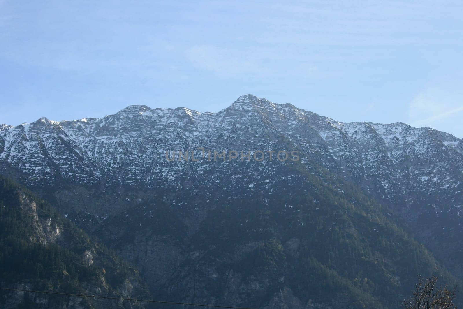 Alpine summits covered with snow, blue sky in the background .