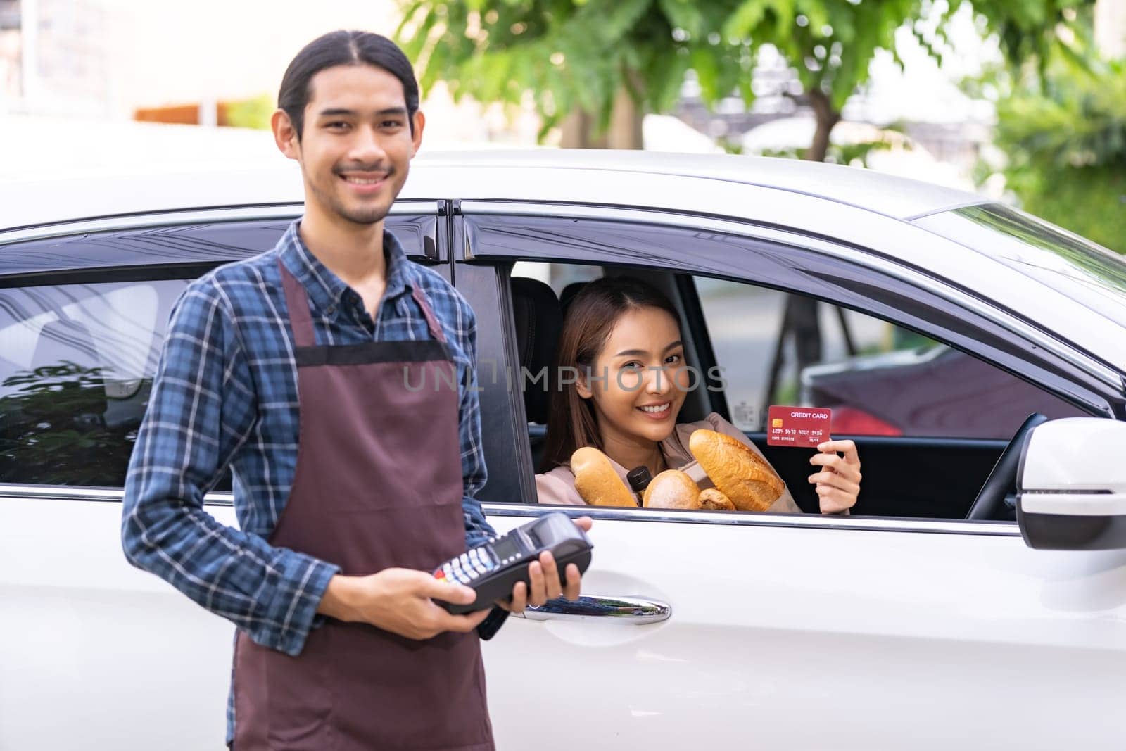 Portrait of asian woman make mobile payment contactless technology for online grocery ordering and drive thru service. Drive through and food online is new normal popular after coronavirus pandemic.