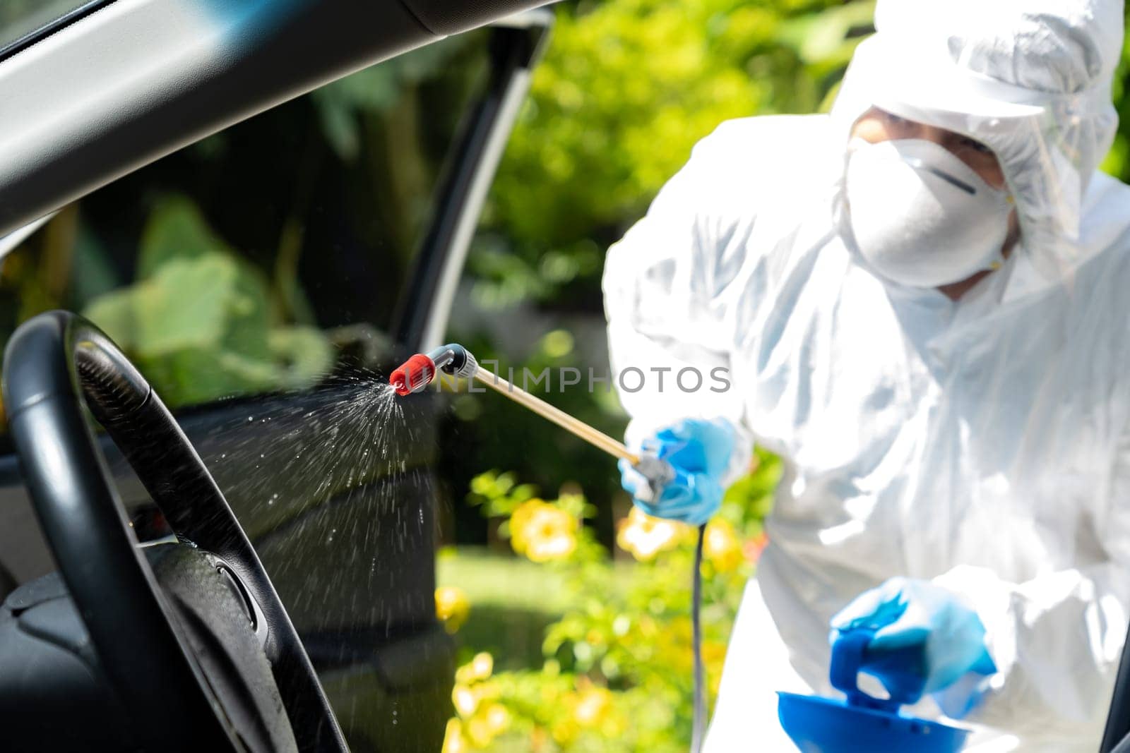 Close up of chemical alcohol spray cleaning inside car to disinfect and decontaminate coronavirus covid-19 by specialist cleaner wearing personal protective equipment PPE. New normal Hygiene concept.