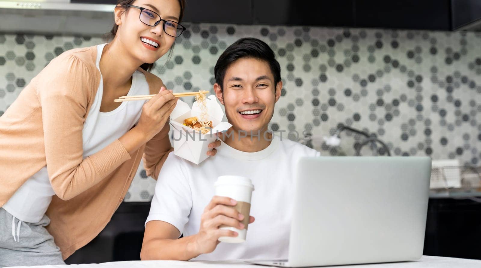 Panoramic asian couple work from home in kitchen and eat delivery chinese take away food and take out coffee while city lockdown from covid-19 pandemic. New Normal lifestyle working from home.