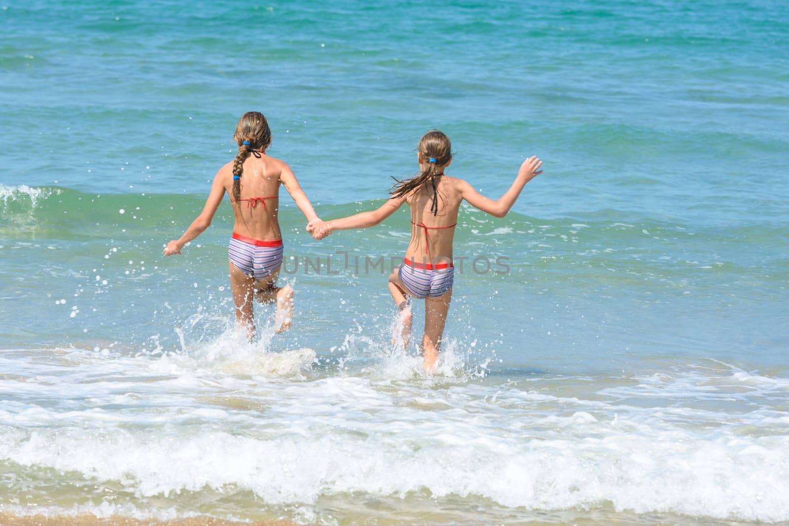 Girlfriends ran into the sea, view from the back