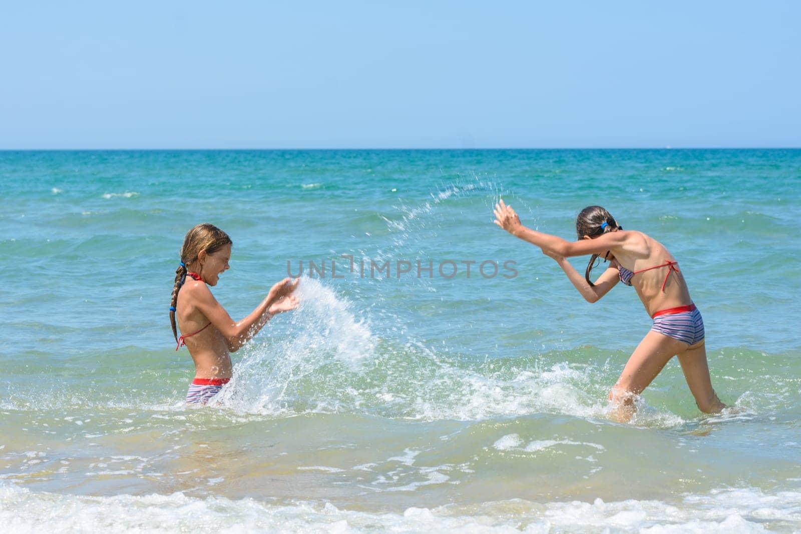 Girls splash on each other on the sea coast