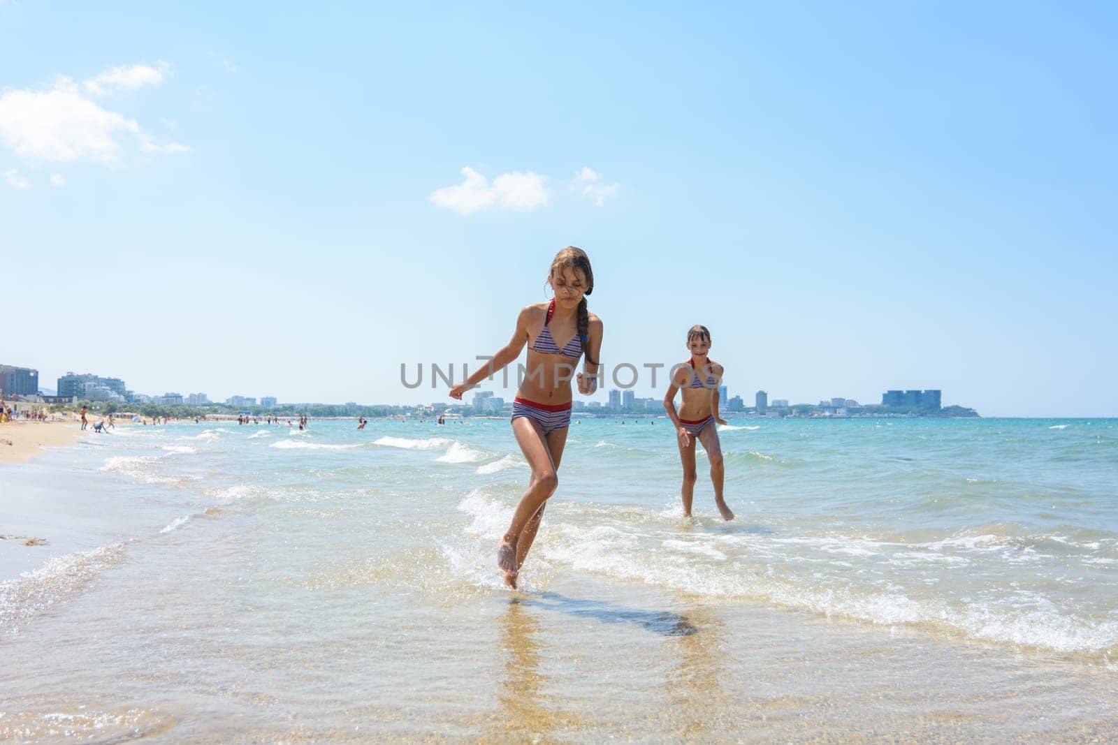 Two girlfriends run along the coastal strip of the sea coast