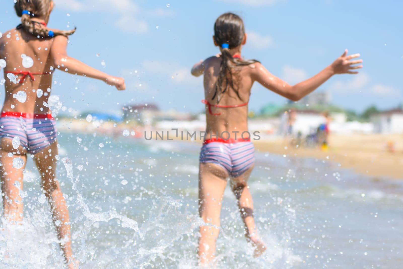 Spray soars after children run along the seashore