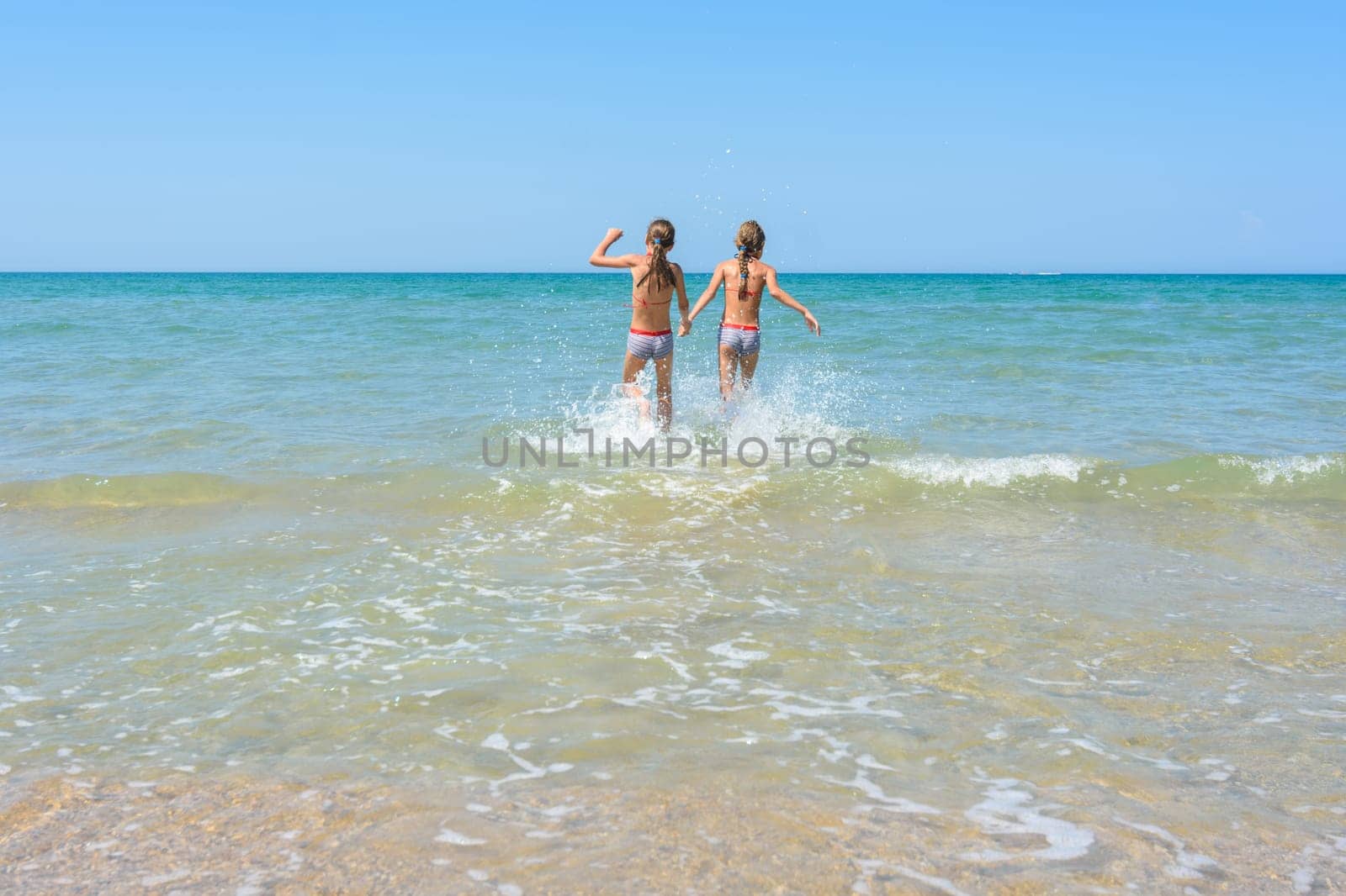 Girls run in the water swimming in shallow water