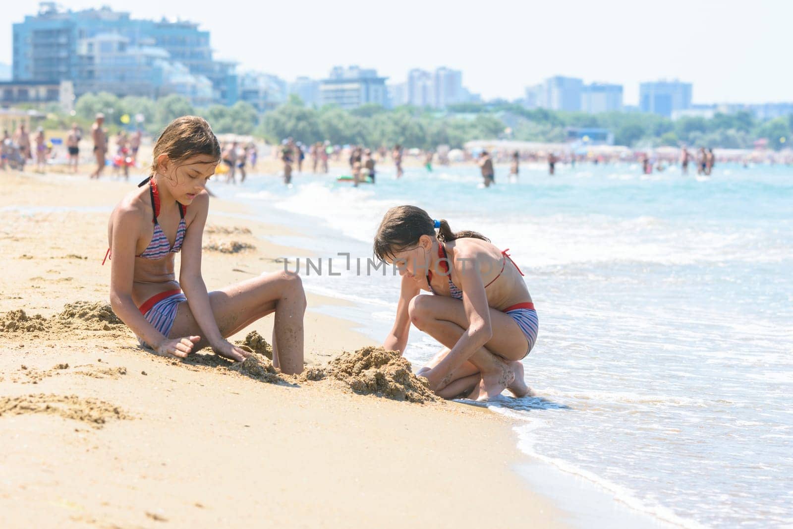 Girls on the seashore make sand castles