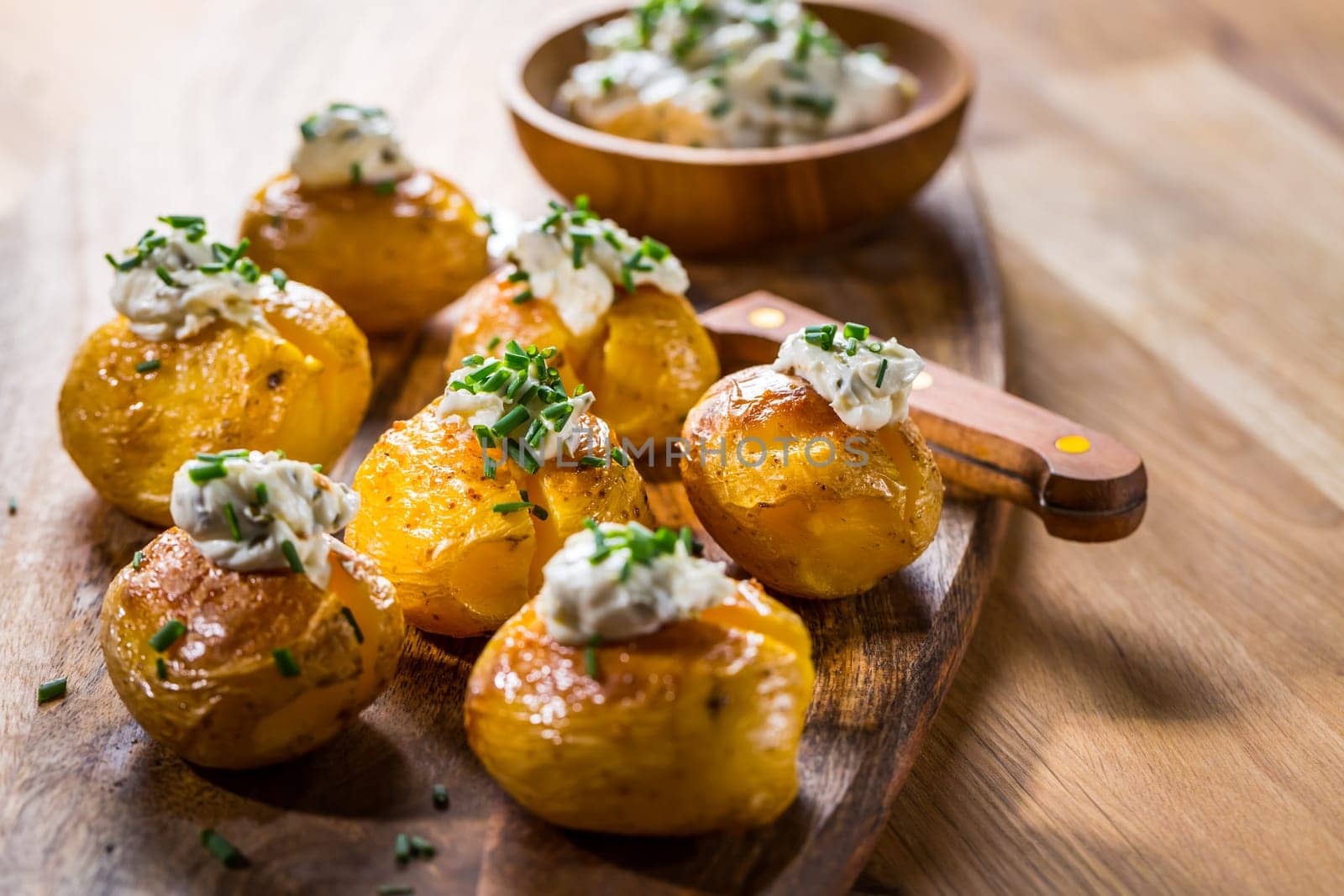Small oven baked potatoes with sour cream with butter and chives