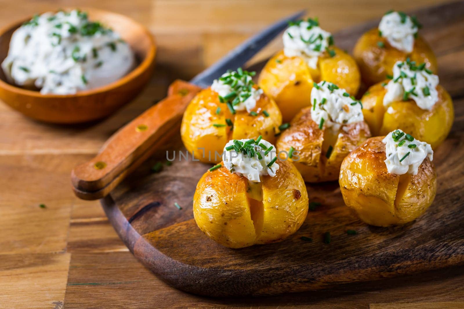 Small oven baked potatoes with sour cream with butter and chives