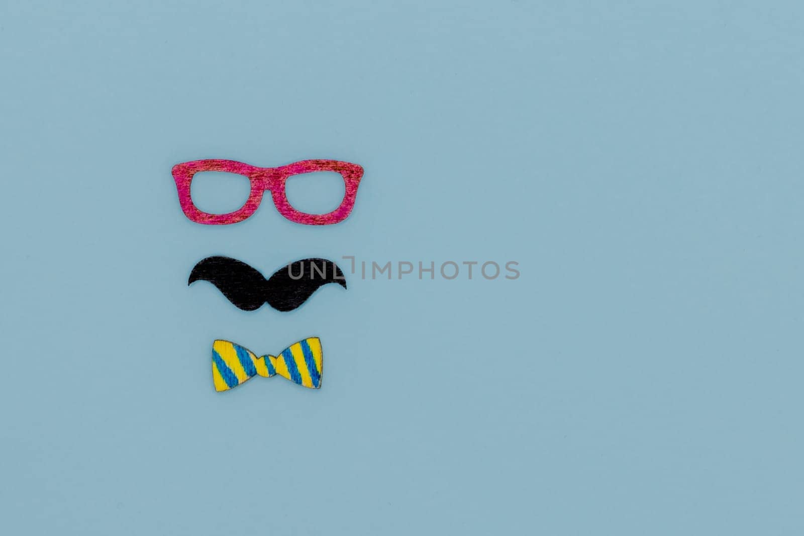 Concept image with glasses, moustache and bow tie on light blue background as resource for creative projects, copy space on the right