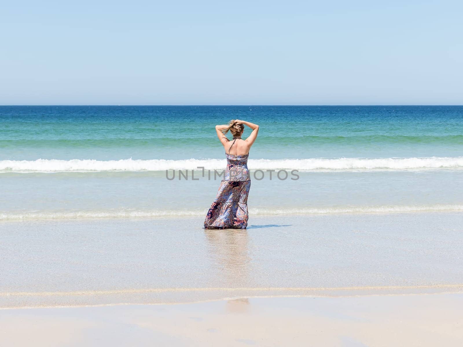 Woman relaxing on the beach with her hands on the back of her head enjoying her freedom facing the sea