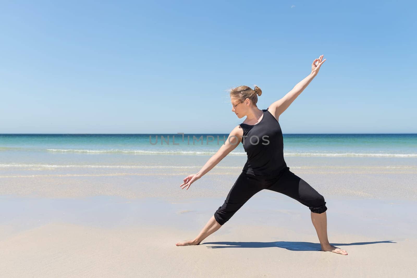 woman in meditation pose at the beach with the sea in the background