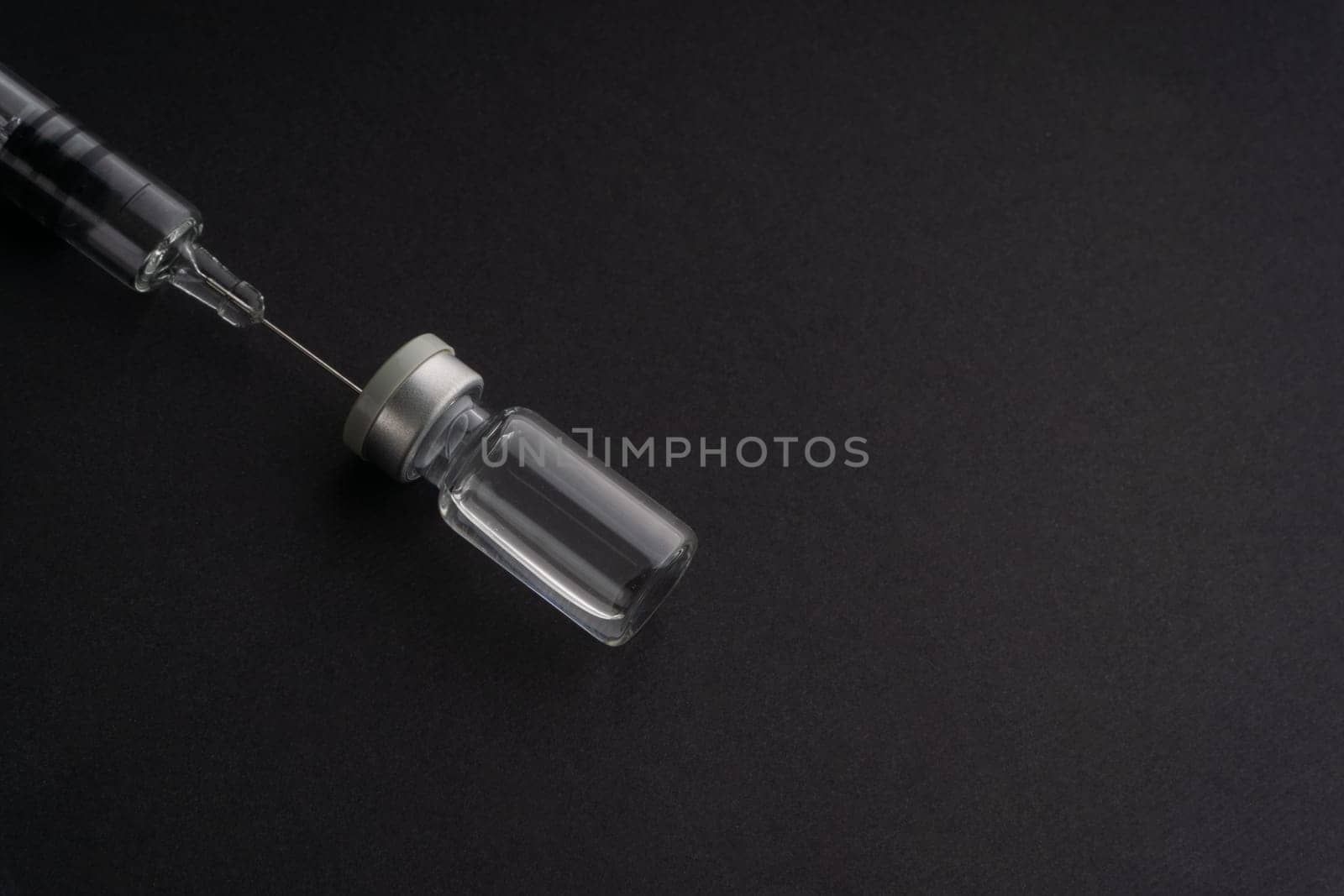 Closeup syringe and vials on black background. Healthcare dan Copy Space concept