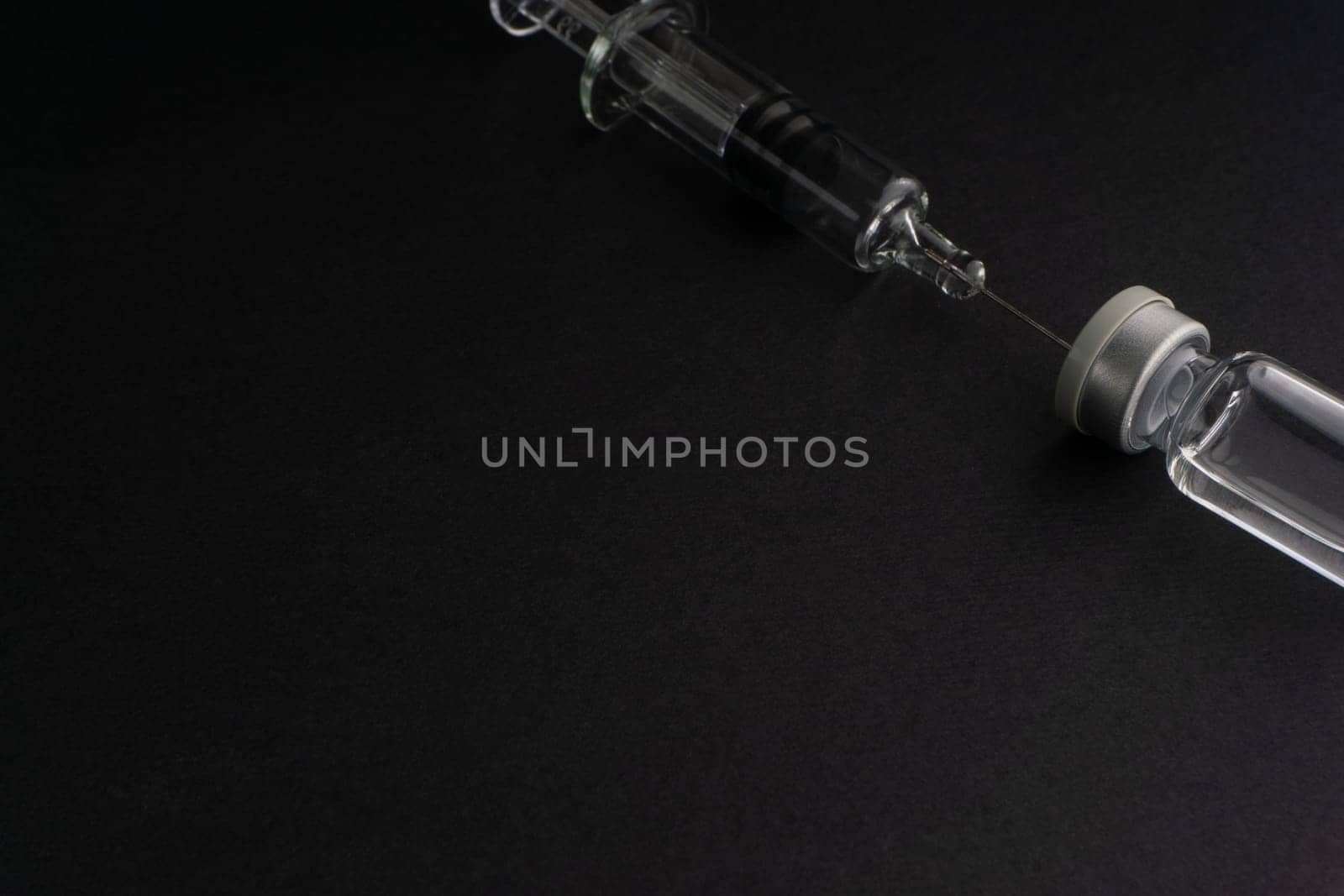 Closeup syringe and vials on black background. Healthcare dan Copy Space concept