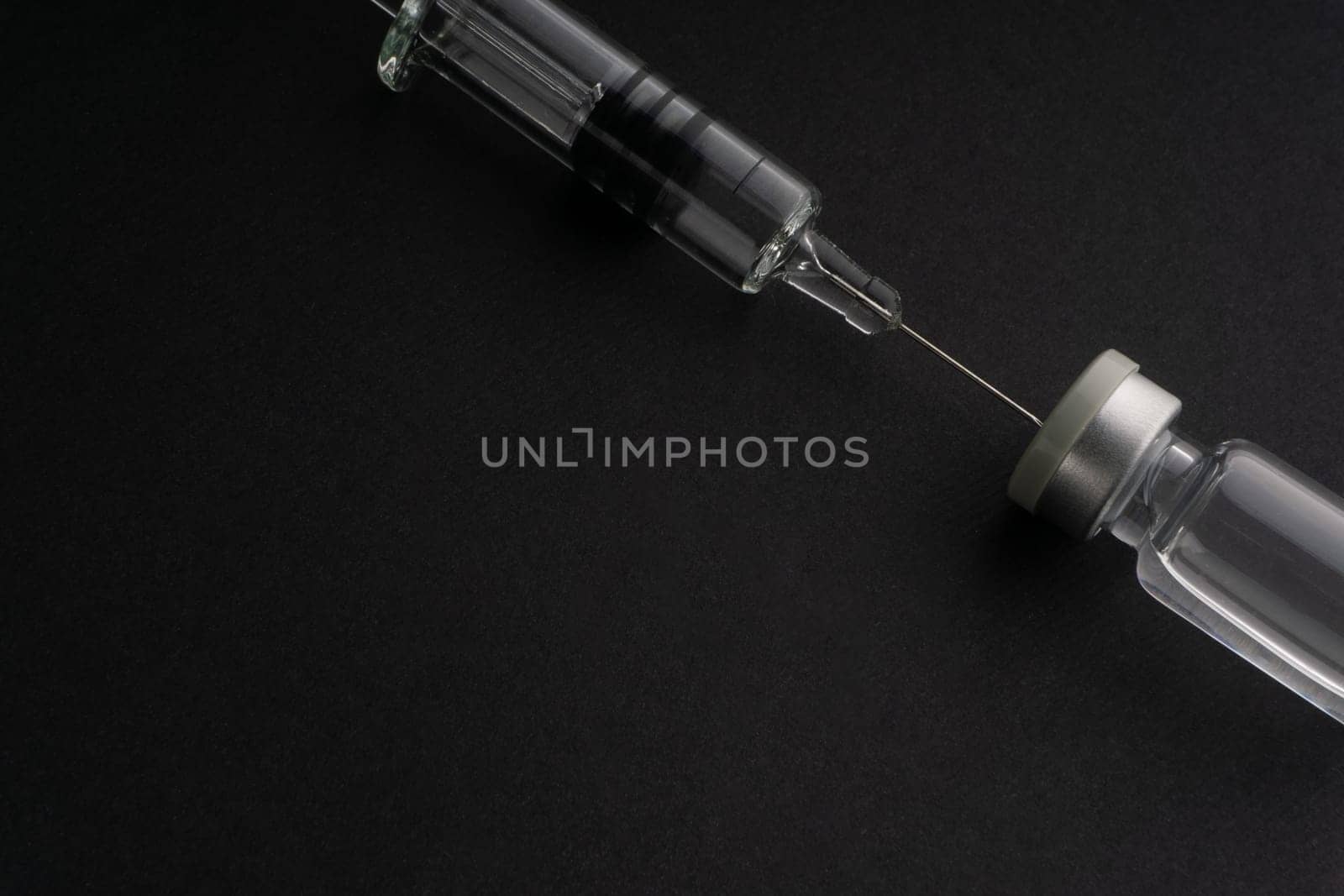 Closeup syringe and vials on black background. Healthcare dan Copy Space concept