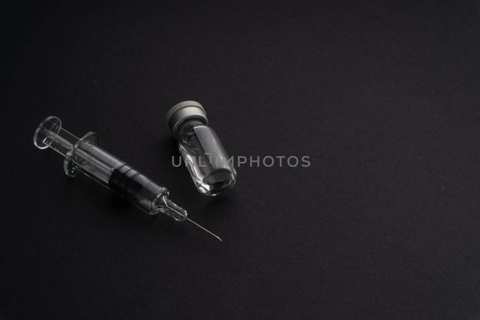 Closeup syringe and vials on black background. Healthcare dan Copy Space concept