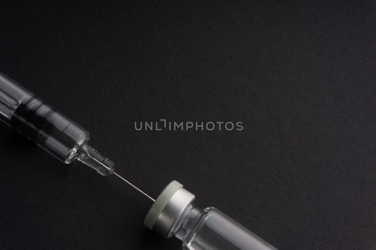 Closeup syringe and vials on black background. Healthcare dan Copy Space concept