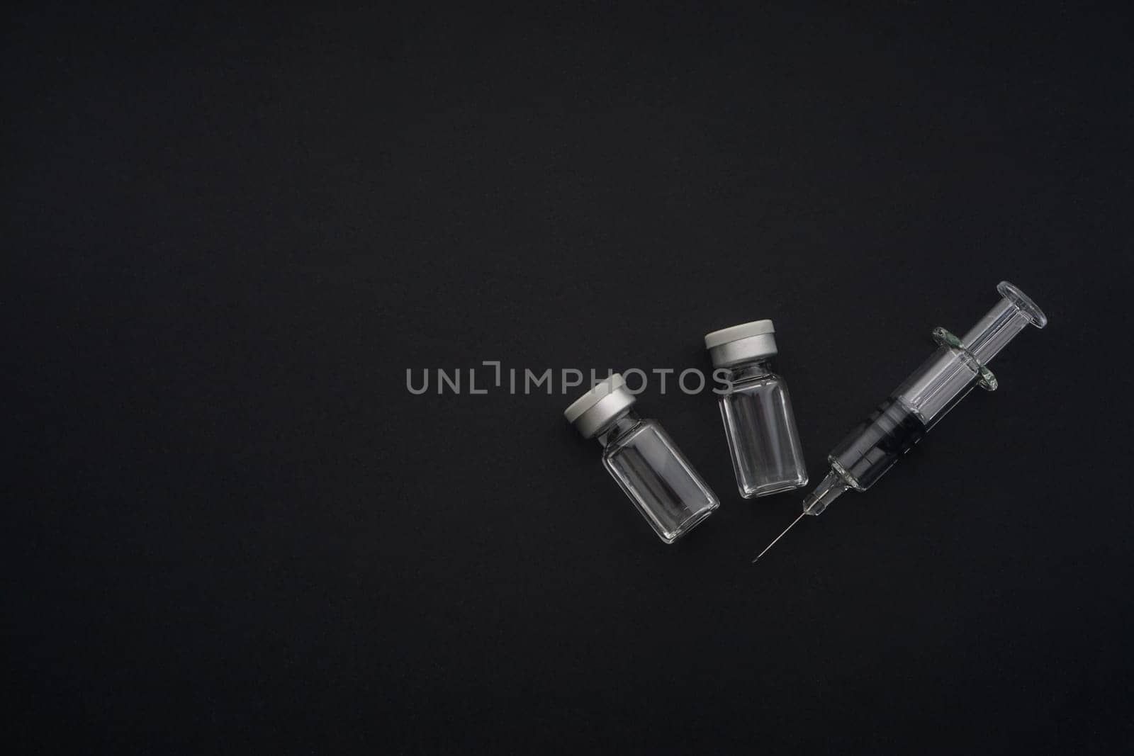 Closeup syringe and vials on black background. Healthcare dan Copy Space concept