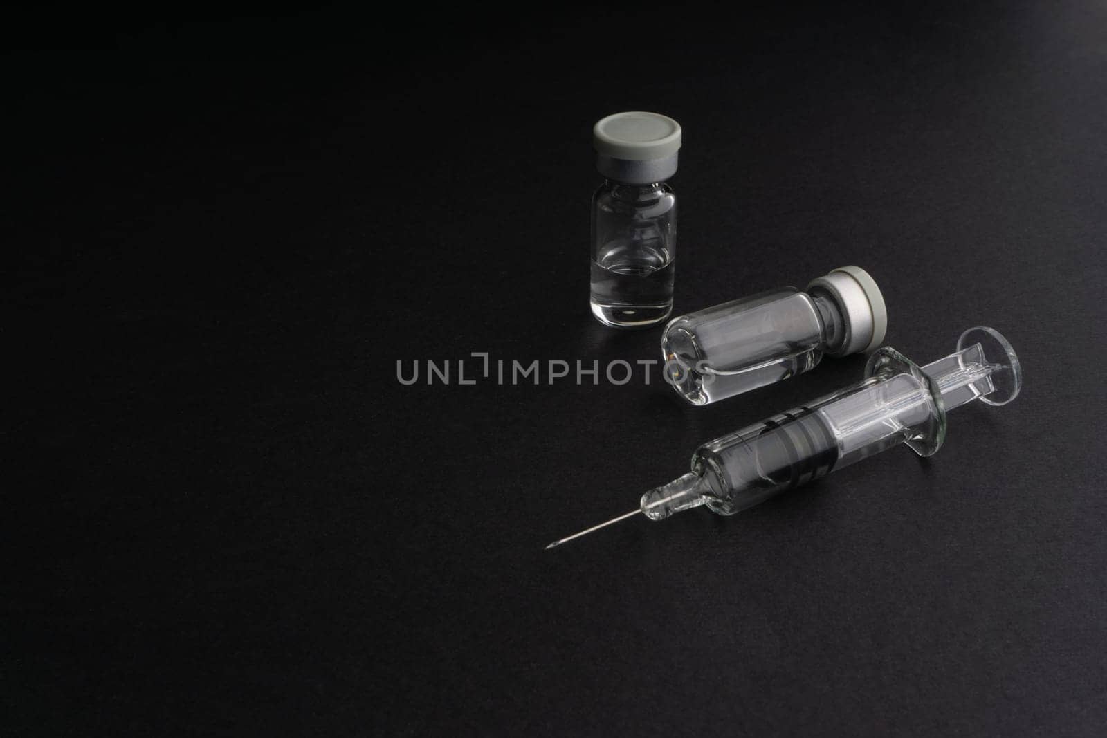 Closeup syringe and vials on black background. Healthcare dan Copy Space concept