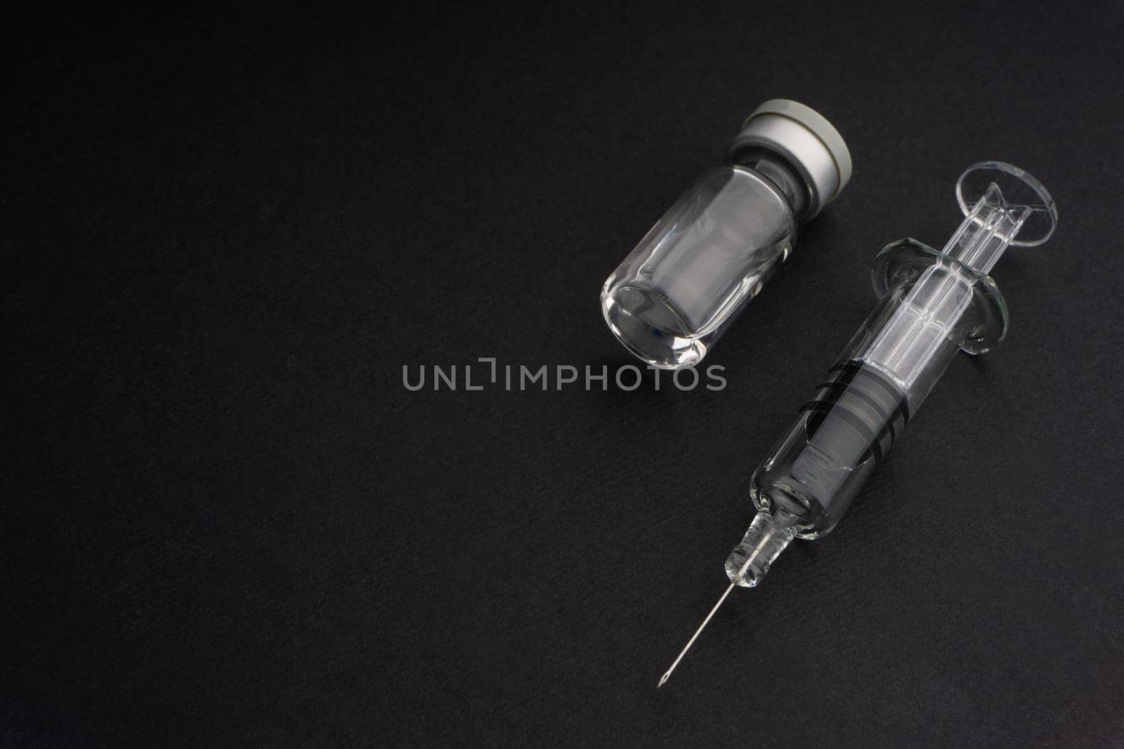Closeup syringe and vials on black background. Healthcare dan Copy Space concept