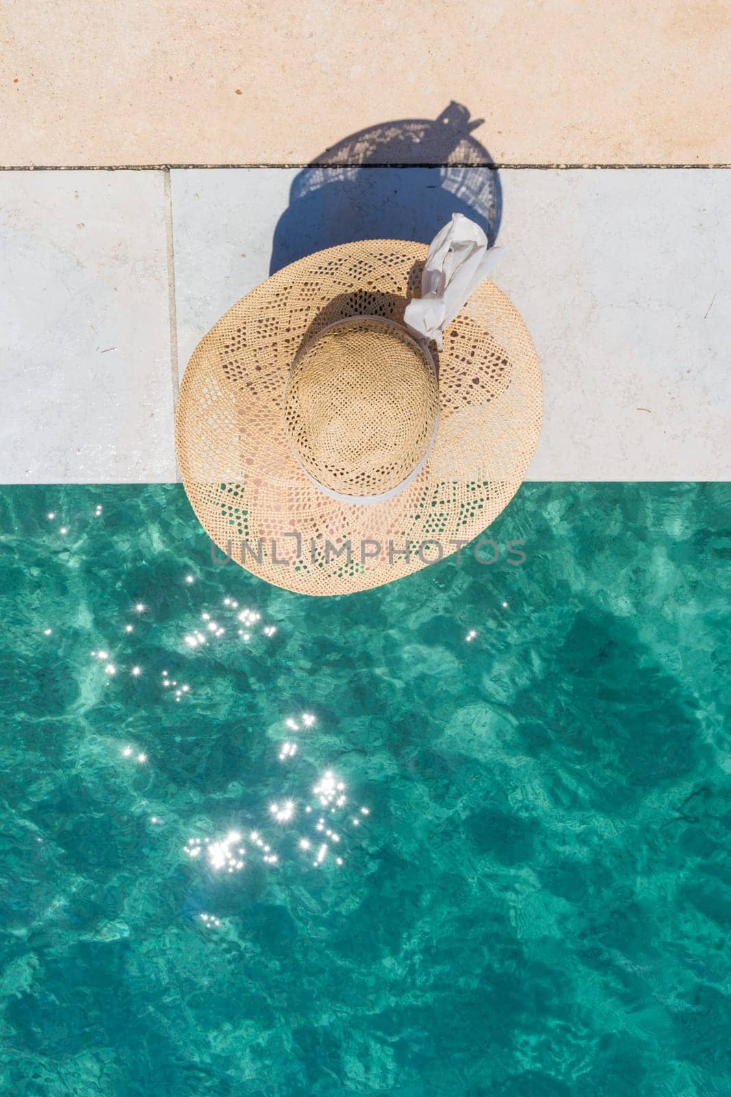 Graphic image of top down view of woman wearing big summer sun hat relaxing on pier by clear turquoise sea.
