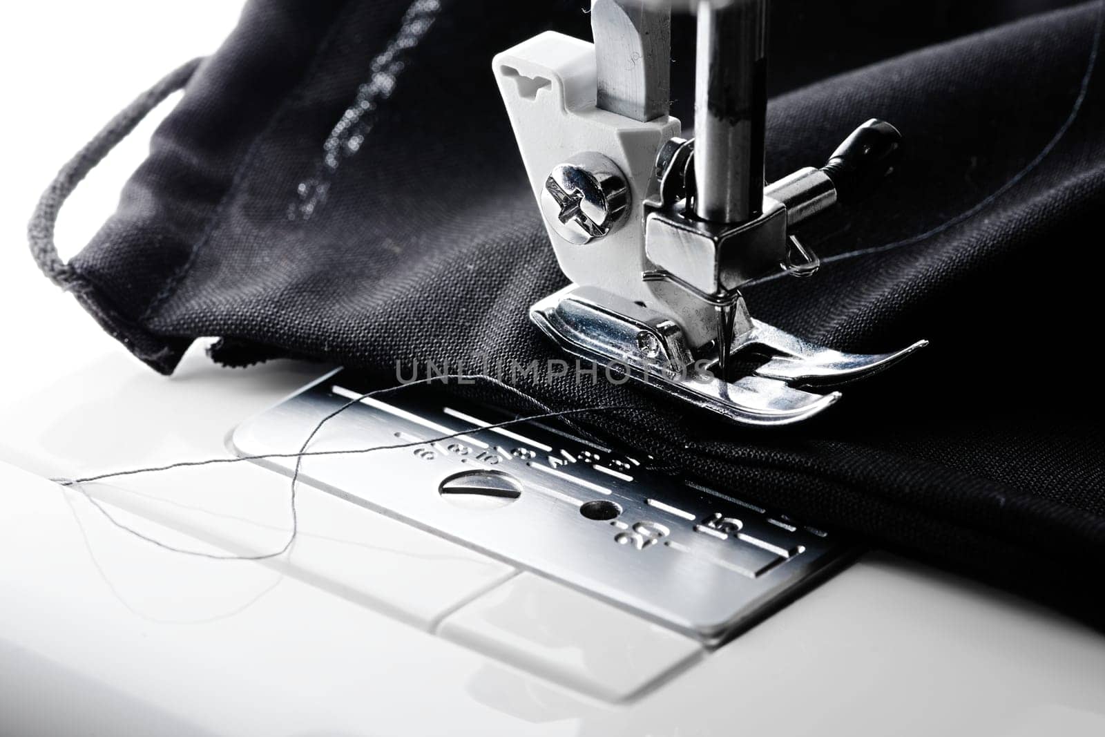 Black face mask contrasts to bright white sewing machine. Home made mask as england brings in compulsory face coverings due to the coronavirus.
